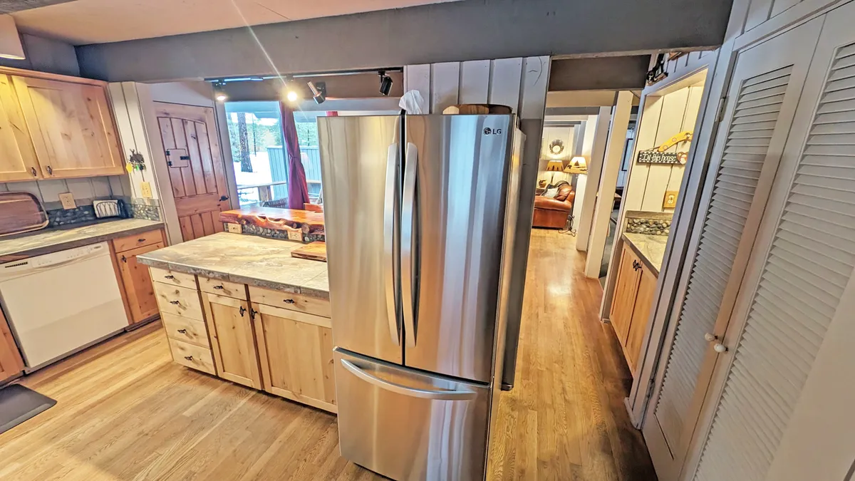 A chef-inspired kitchen with a gleaming stainless steel refrigerator, warm wooden cabinetry, and a central island perfect for meal prep or casual gatherings. The scene radiates hospitality and readiness for group cooking sessions or lively family meals.