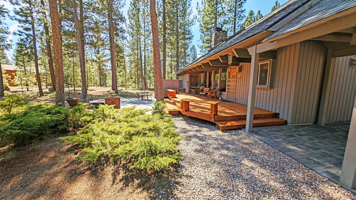 This image features a spacious wooden deck nestled among mature trees, complete with outdoor seating. The area is inviting, ideal for relaxing after a day of activities or gathering for a meal beneath the open sky.